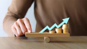 Money leverage and inflation balance. Businesswoman Balancing Stacked Coins With Finger On Wooden Seesaw