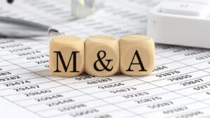 wooden cubes with the word M and A on financial background with chart, calculator, pen and glasses, business concept.