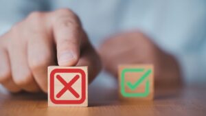 person pointing to a block with red x on it, with a block with a green checkbox on it out of focus