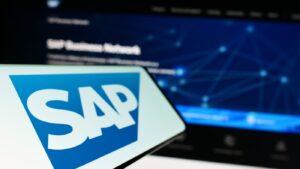 Cellphone with logo of German software company SAP SE on screen in front of business website. Focus on left of phone display. Unmodified photo
