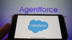 Agentforce in background blurred with mobile phone in foreground with salesforce logo
